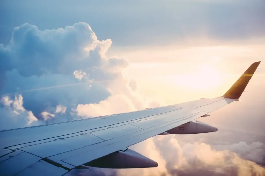 A view of an airplane wing flying above the clouds representing the benefits of the best travel and rewards credit cards