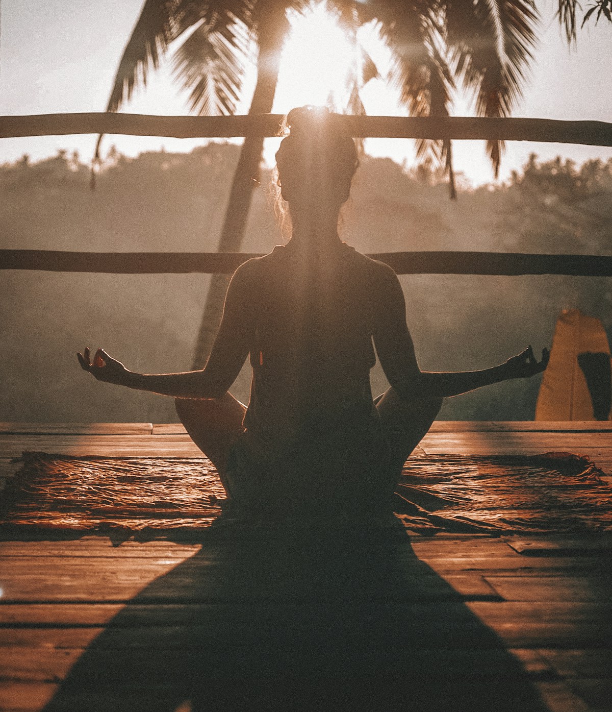 Person practicing morning meditation outdoors at sunrise with natural light exposure