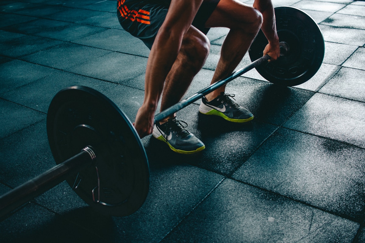 Person performing resistance training with dumbbells in a well-lit gym environment