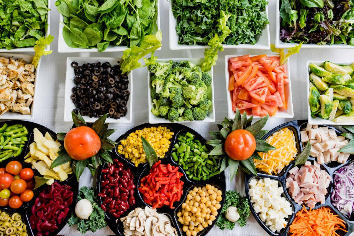 Colorful array of whole foods including vegetables, fermented foods, and protein sources on a wooden table