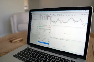 Financial advisor analyzing market charts on a laptop and smartphone.