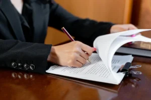 A prenuptial agreement lawyer in a black suit signing legal documents on a wooden desk